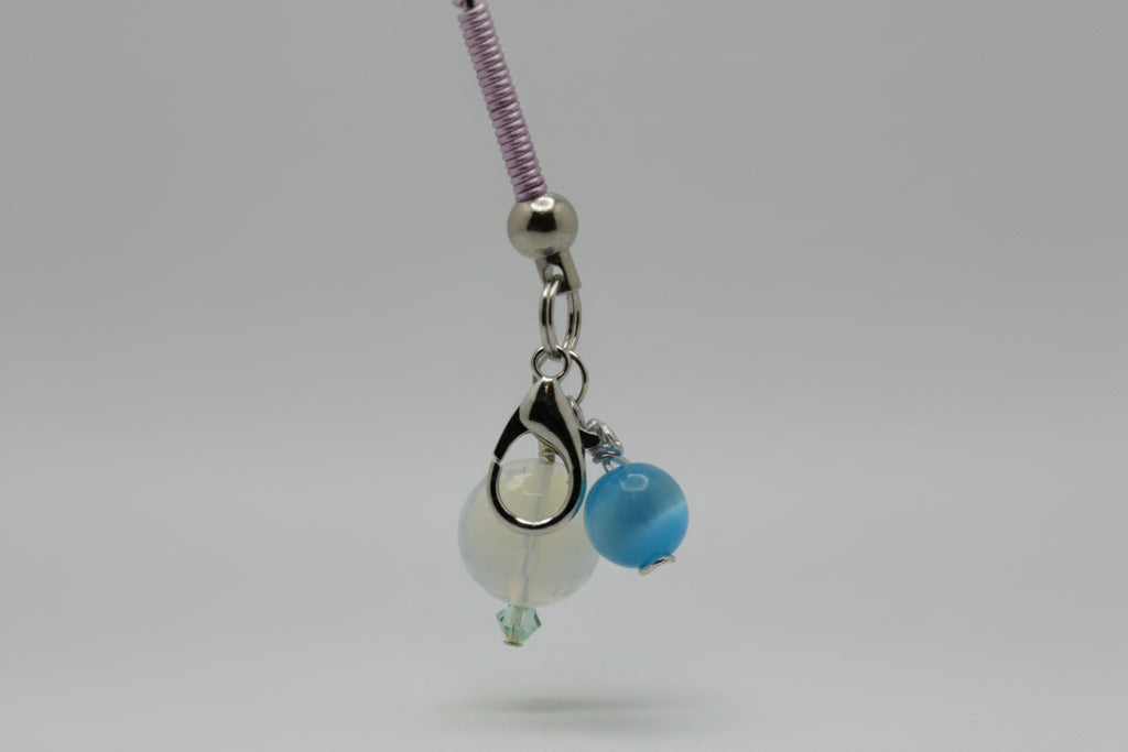 roach clip base with a silver clasp, a white bead, a blue bead, and a purple braided section on a light gray background.