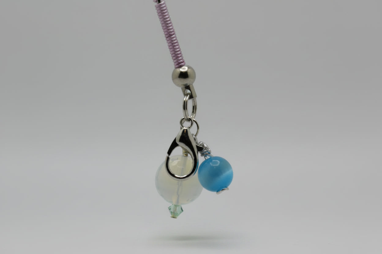 roach clip base with a silver clasp, a white bead, a blue bead, and a purple braided section on a light gray background.